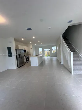 a view of empty room with kitchen and window