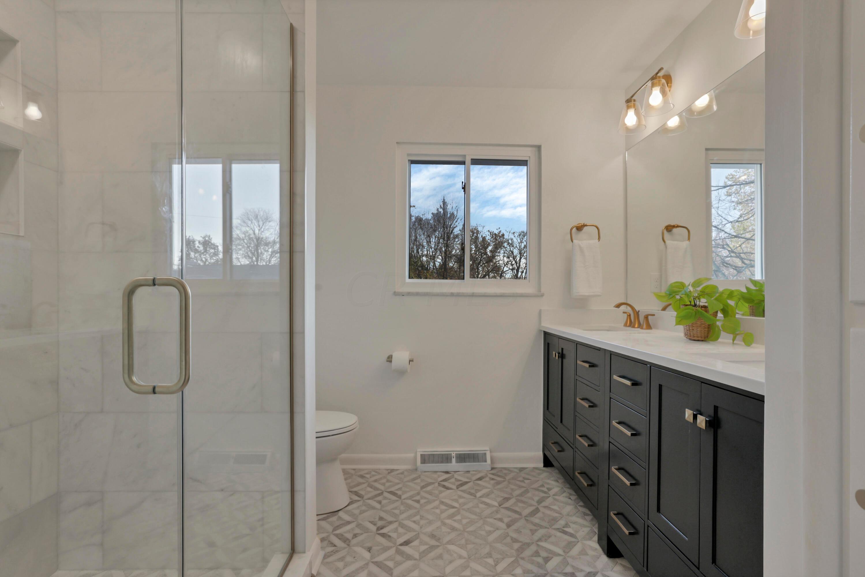 2275 Haverford Road Columbus, OH 43220 - Photo 27 of 57 The en suite bathroom with a double vanity sink, new fixtures, updated lighting, tile shower with built-in niche and custom glass door.