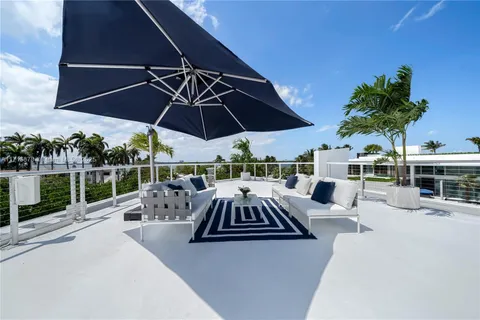 a view of a patio with couches table and chairs under an umbrella