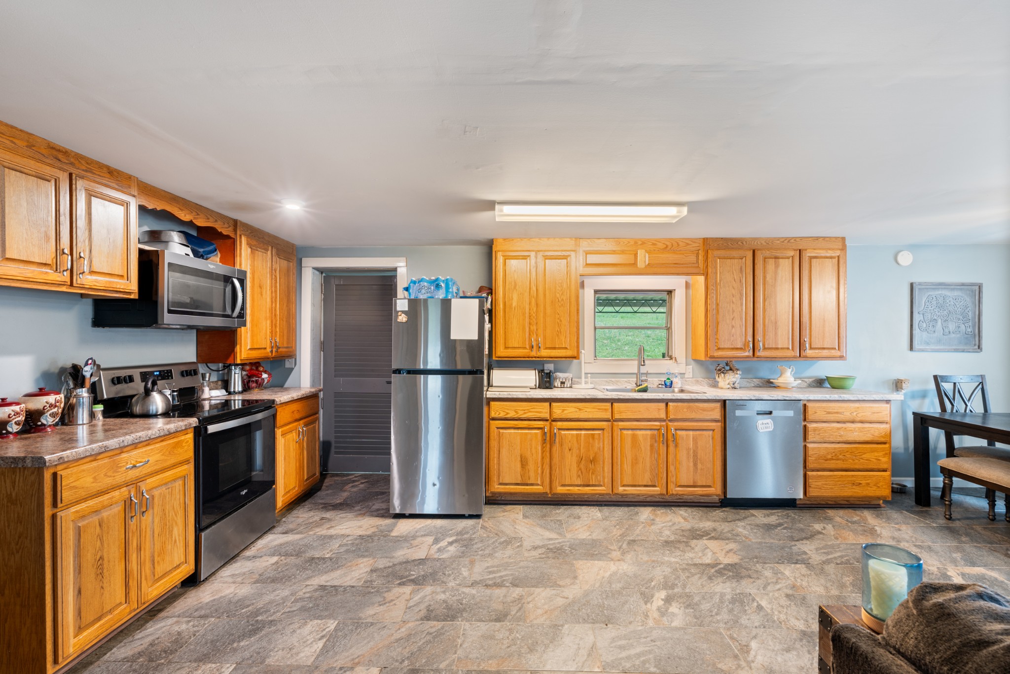 121 Deer Creek Road McEwen, TN 37101 - Photo 22 of 35 a kitchen with stainless steel appliances granite countertop a stove top oven a sink dishwasher a dining table and chairs with wooden floor