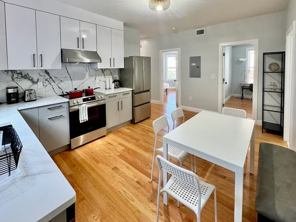 a kitchen with stainless steel appliances kitchen island granite countertop a sink dishwasher a stove a refrigerator a microwave oven with cabinets and wooden floor
