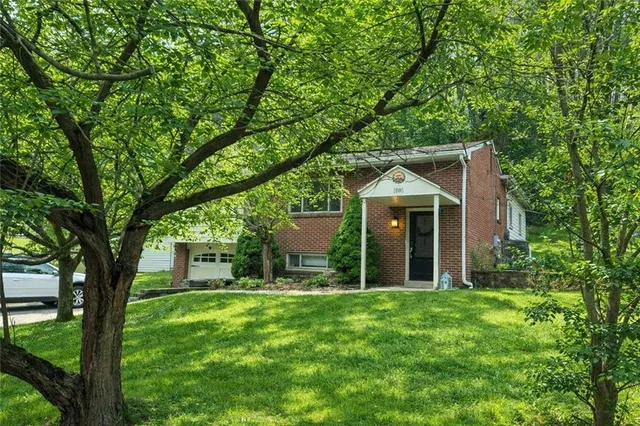 a view of a house with a yard and large trees