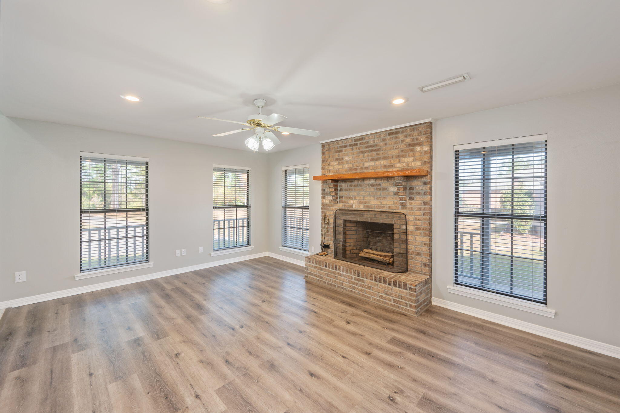 1136 10 Lake Drive DeFuniak Springs, FL 32433 - Photo 11 of 53 an empty room with windows fireplace and wooden floor