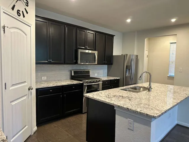 a view of a living room and kitchen with stainless steel appliances