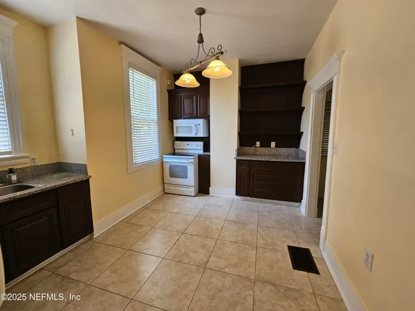 a kitchen with granite countertop a refrigerator and a stove top oven