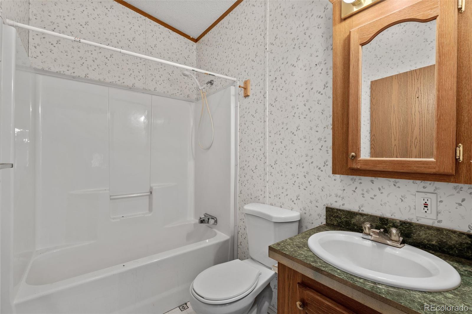 1711 Witcher Mtn. Road Guffey, CO 80820 - Photo 26 of 41 a bathroom with a granite countertop sink toilet mirror and shower