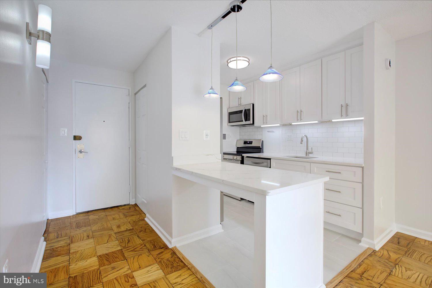 1718 P Street Northwest, Unit 411 Washington, DC 20036 - Photo 5 of 24 a kitchen with kitchen island white cabinets and appliances