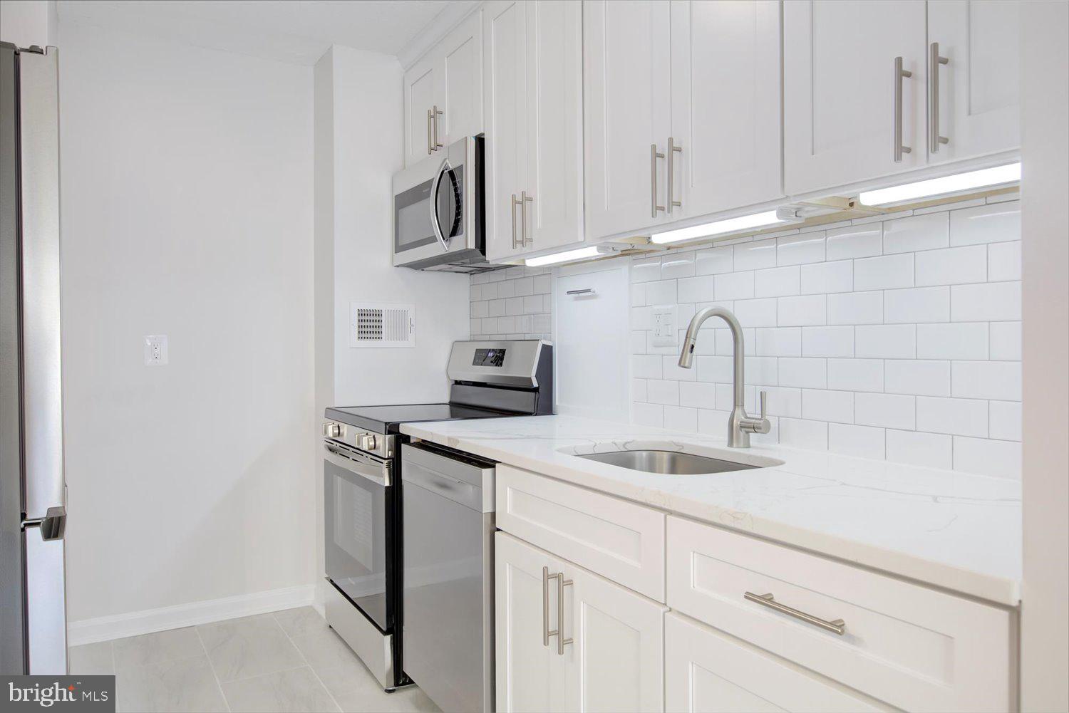 1718 P Street Northwest, Unit 411 Washington, DC 20036 - Photo 7 of 24 a kitchen with stainless steel appliances granite countertop white cabinets and a sink