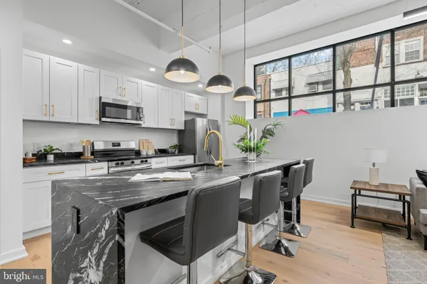 a kitchen with stainless steel appliances granite countertop a stove a sink dishwasher a dining table and chairs with wooden floor