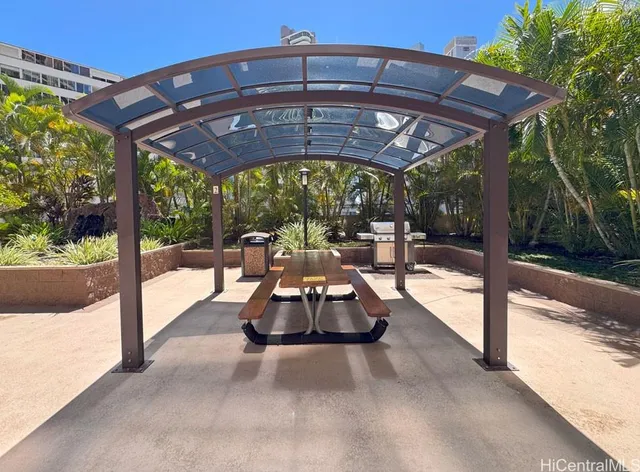a view of a patio with a table and chairs under an umbrella with a small yard