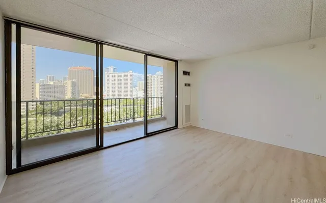 a view of an empty room with wooden floor and a balcony