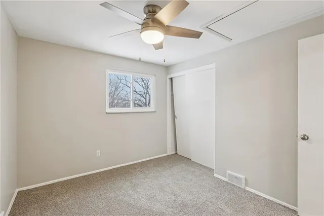 an empty room with a window and a ceiling fan