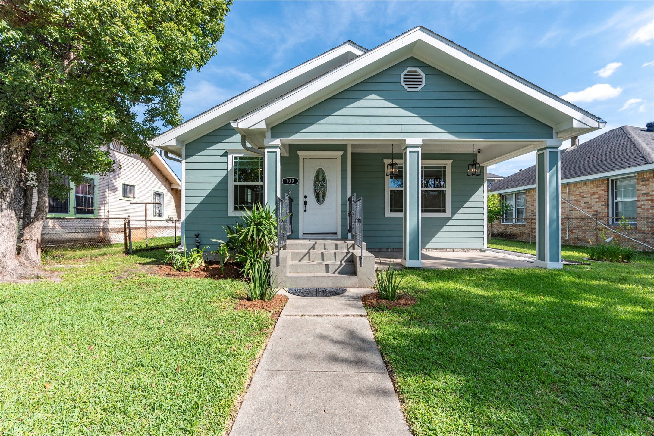 109 Dresden Street Houston, TX 77012 - Photo 1 of 43 Charming single-story home with a welcoming front porch, light blue siding, and white trim. The front yard is well-maintained with a concrete path leading to the entrance, framed by manicured plants and a mature tree. Perfect for cozy living.