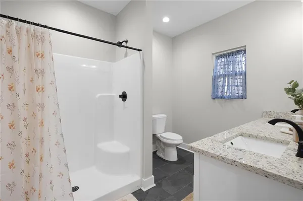 a bathroom with a granite countertop sink toilet and shower