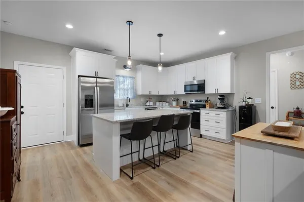 a kitchen with kitchen island granite countertop a sink a center island stainless steel appliances and cabinets