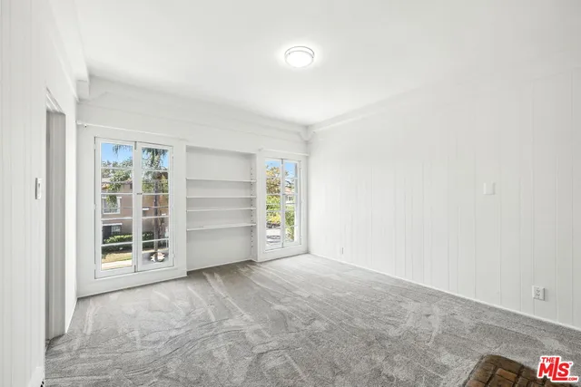a view of an empty room with a window and cabinet