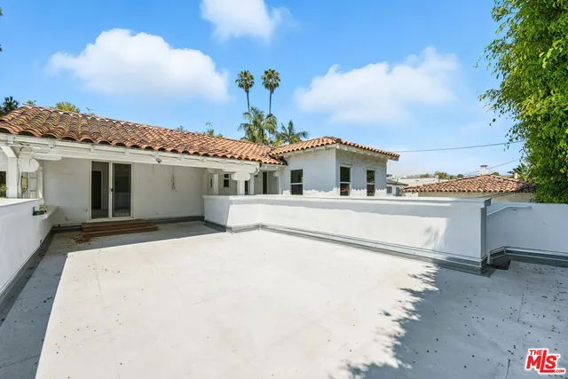 a view of a white house with a yard and potted plants