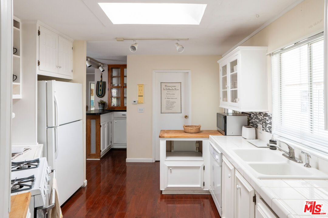 1183 Aztec Topanga, CA 90290 - Photo 18 of 68 a kitchen with stainless steel appliances a sink a stove a refrigerator cabinets and wooden floor