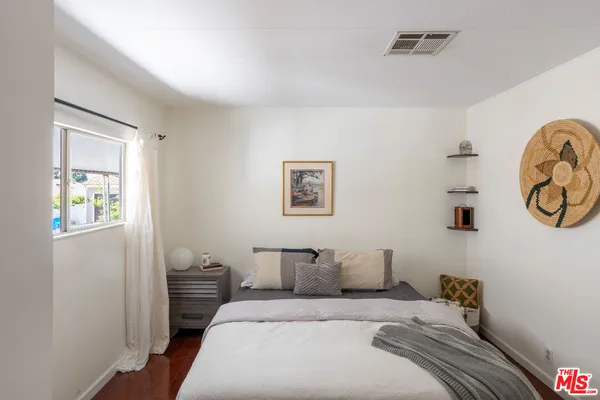 a bedroom with a bed and painting on the wall
