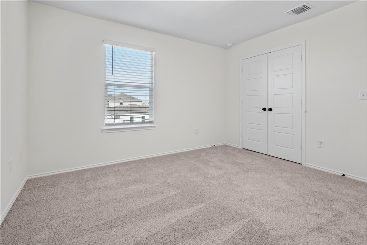 18501 Spotted Eagle Lane Elgin, TX 78621 - Photo 19 of 40 A well-lit bedroom features plush carpeting and a convenient double-door closet.