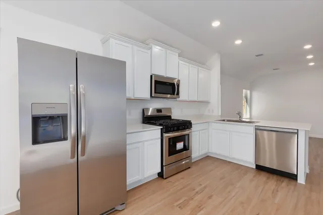 a kitchen with cabinets stainless steel appliances and wooden floor