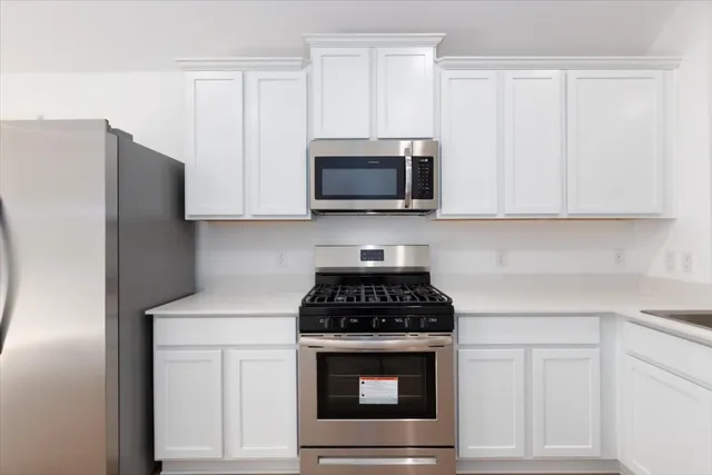 a kitchen with granite countertop white cabinets and stainless steel appliances