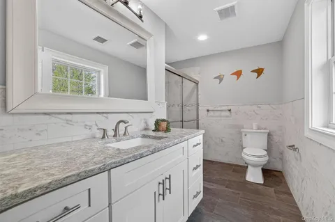 a bathroom with a granite countertop sink a toilet and a mirror