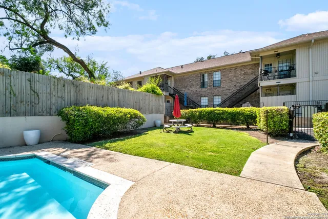 a view of backyard with swimming pool and green space