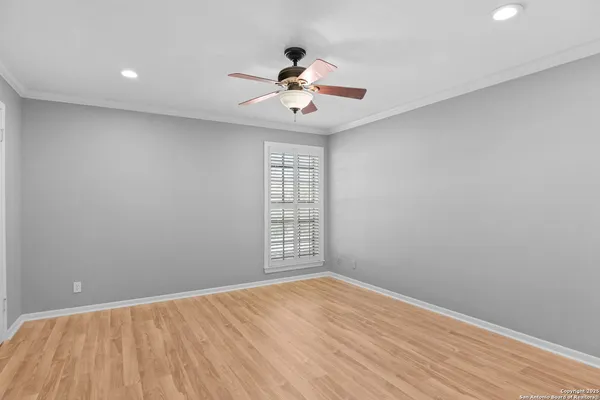 a view of an empty room with wooden floor and a ceiling fan