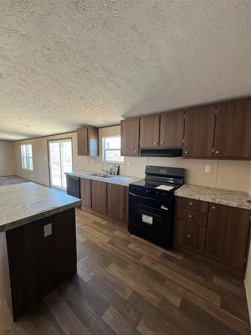 a kitchen with stainless steel appliances granite countertop a stove a sink dishwasher and a refrigerator with wooden cabinets