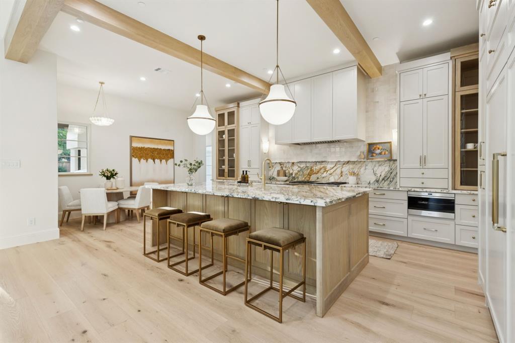 11815 Jamestown Road Dallas, TX 75230 - Photo 11 of 39 a open kitchen with granite countertop a stove a sink a dining table and chairs with wooden floor