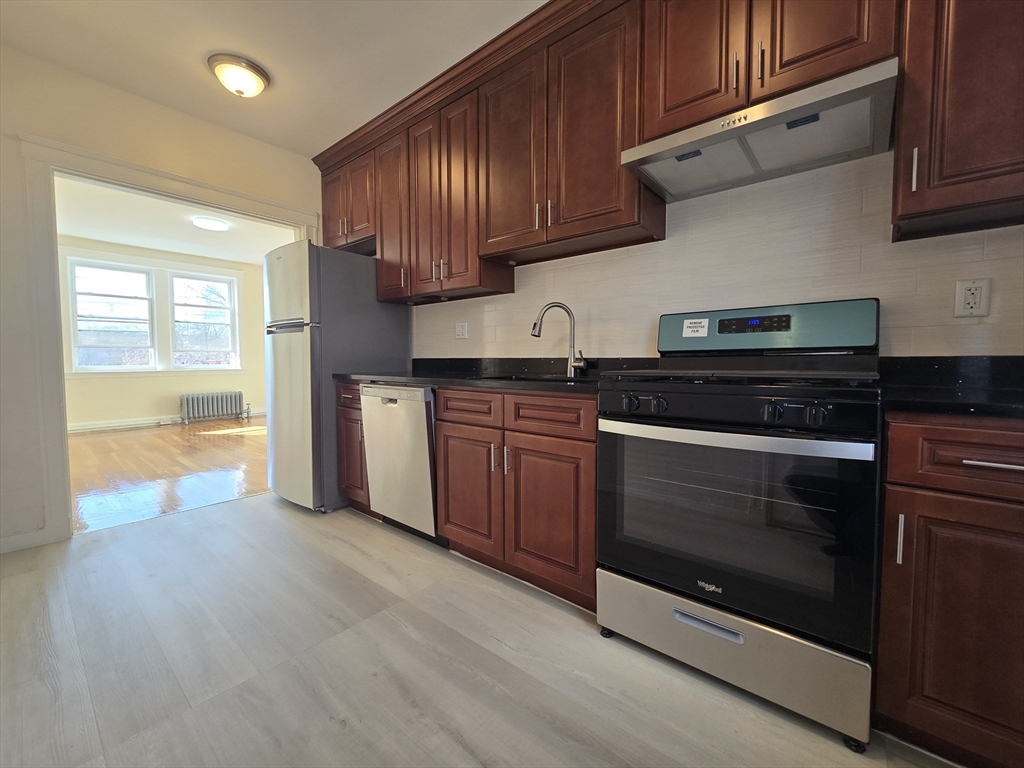 183 Kent Street, Unit 5 Brookline, MA 02446 - Photo 1 of 9 a kitchen with stainless steel appliances granite countertop wooden cabinets and a stove top oven