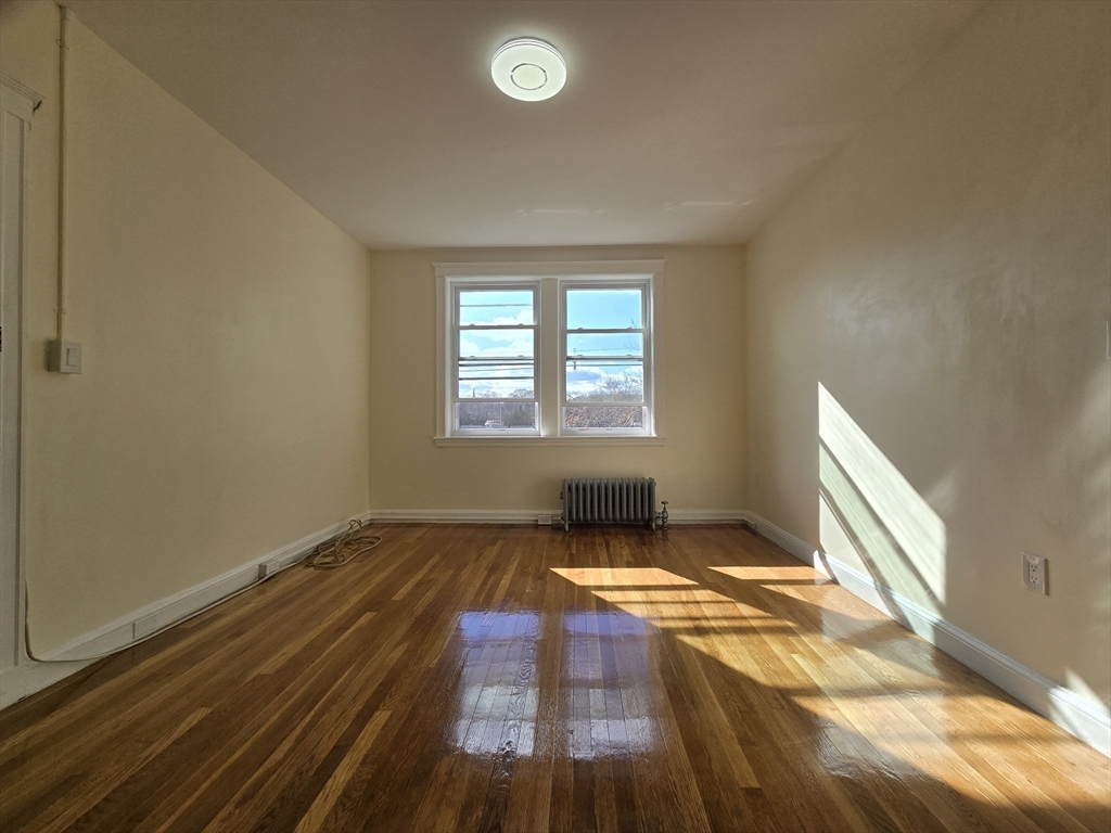 183 Kent Street, Unit 5 Brookline, MA 02446 - Photo 4 of 9 a view of an empty room with wooden floor and a window