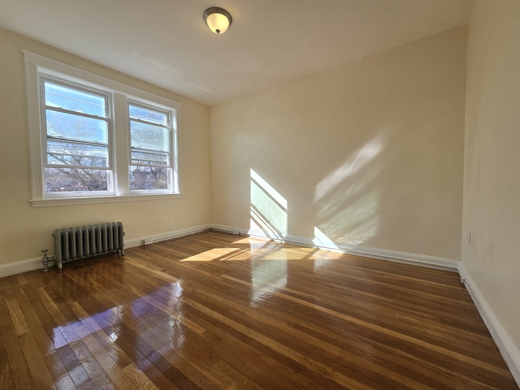 183 Kent Street, Unit 5 Brookline, MA 02446 - Photo 5 of 9 a view of an empty room with wooden floor and a window