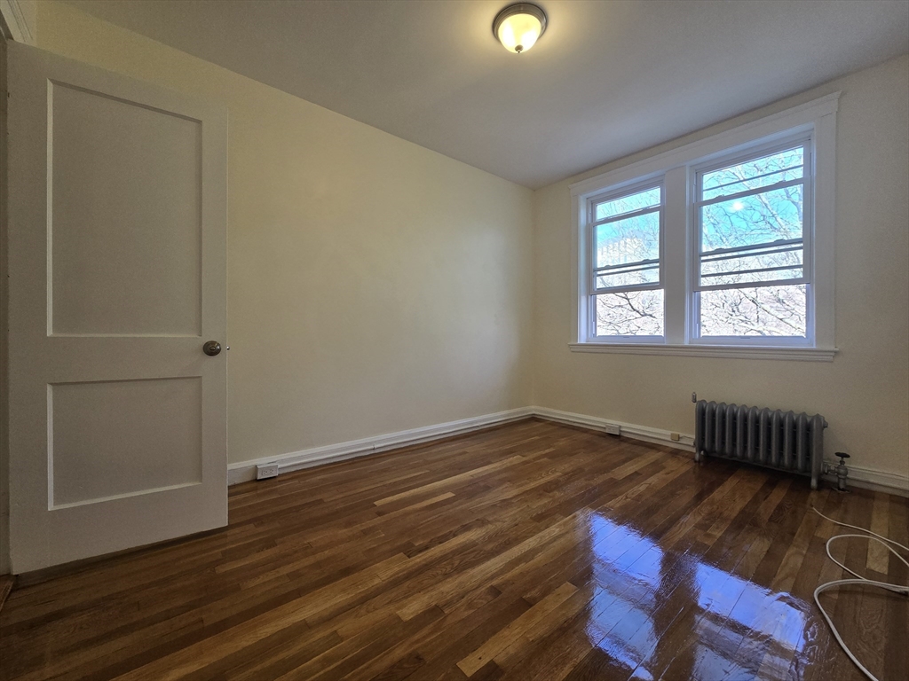 183 Kent Street, Unit 5 Brookline, MA 02446 - Photo 8 of 9 a view of an empty room with wooden floor and a window