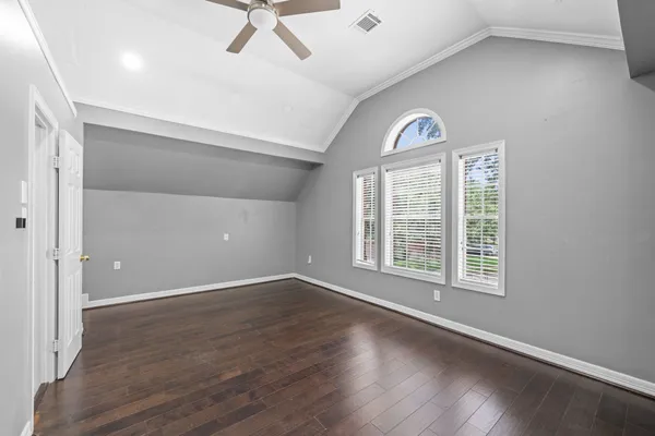 an empty room with wooden floor fan and windows