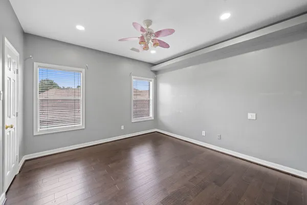 an empty room with windows and chandelier fan