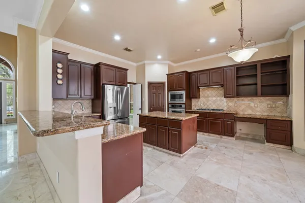 a large kitchen with kitchen island a large counter top stainless steel appliances and cabinets