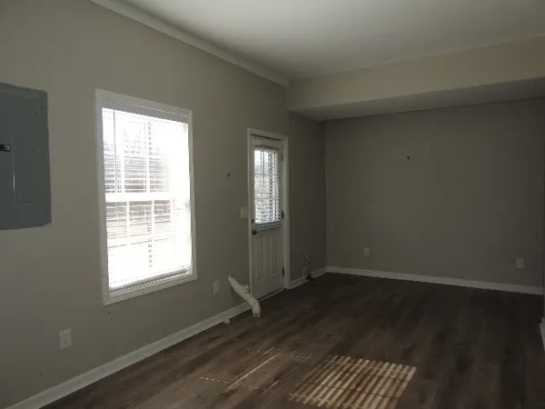 an empty room with wooden floor and windows
