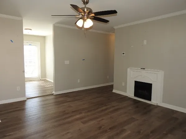 an empty room with wooden floor chandelier fan and windows