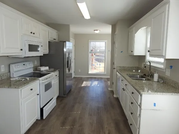 a kitchen with granite countertop a sink a counter top space stainless steel appliances and cabinets
