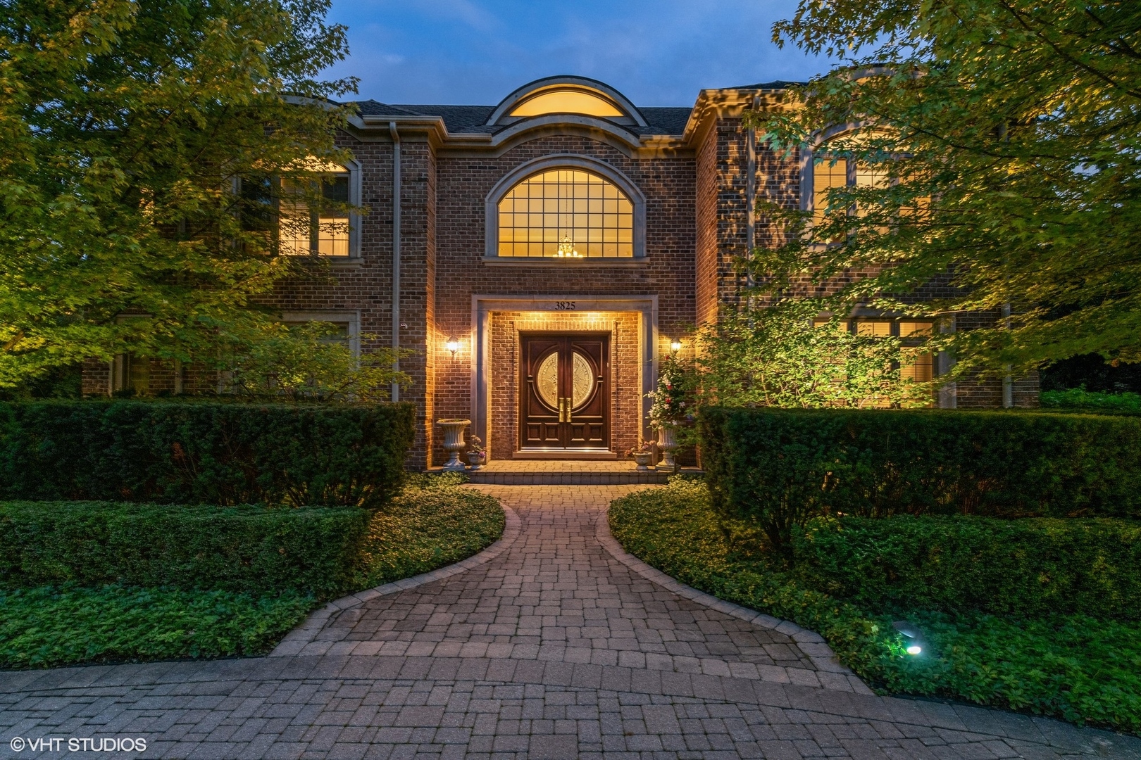 a view of a brick house with a big yard and plants
