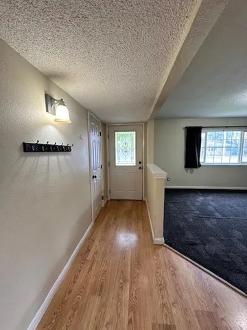 a view of an empty room with wooden floor and a window