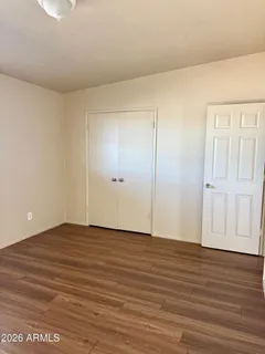 a view of an empty room with wooden floor and closet