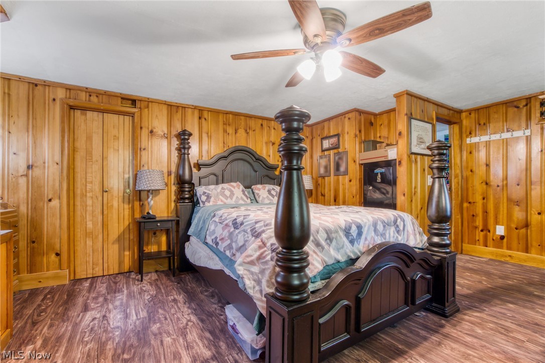 15221 Thompson Road Thompson, OH 44086 - Photo 19 of 31 Bedroom featuring ceiling fan, wood walls, and dark wood-type flooring