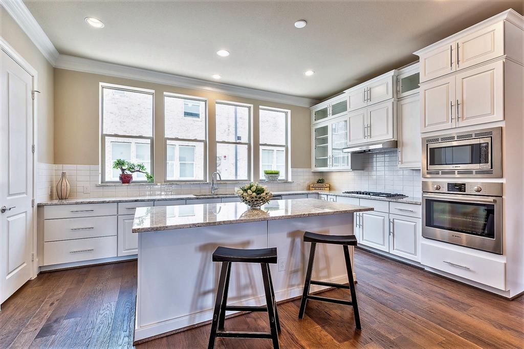 a kitchen with stainless steel appliances granite countertop white cabinets a stove a sink and a refrigerator