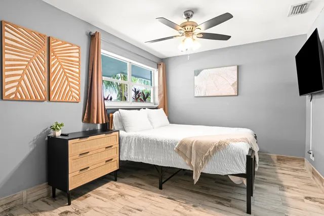 a bedroom with a bed window and a flat screen tv