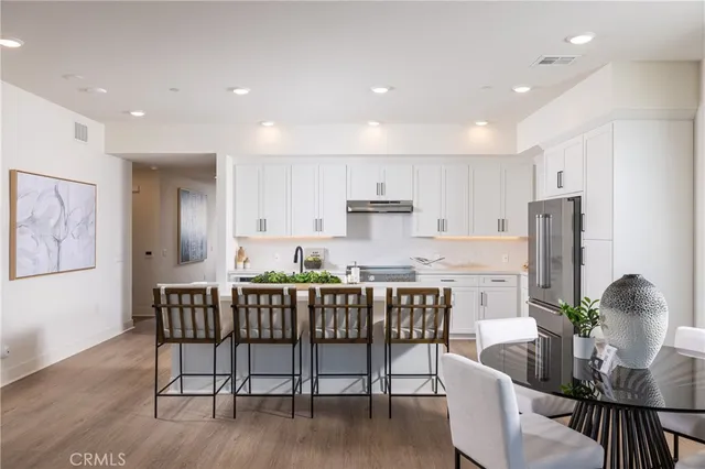 a dining room with stainless steel appliances a dining table chairs and wooden floor