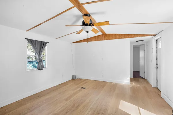 a view of empty room with wooden floor and fan