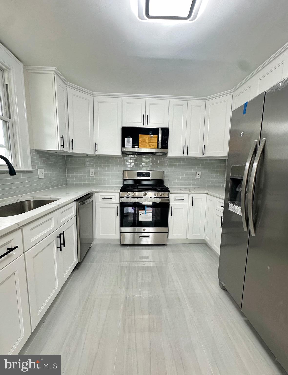 603 Brookwood Road Baltimore, MD 21229 - Photo 10 of 33 a kitchen with granite countertop a refrigerator a stove a sink and white cabinets